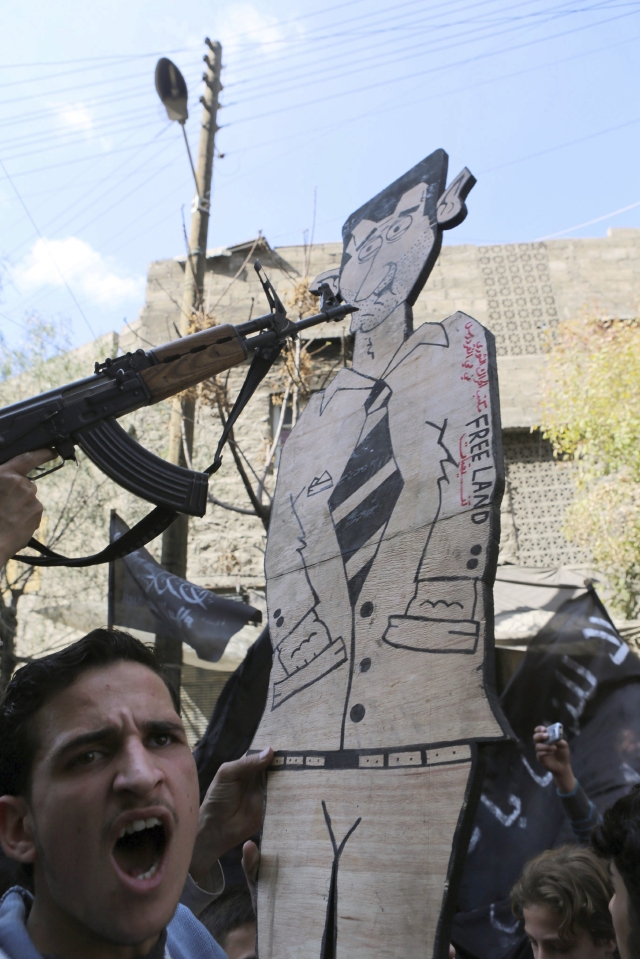 Apuntan con un arma a la figura  de Al Assad,   en Alepo, ayer.