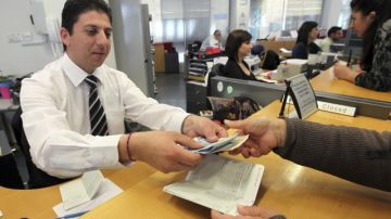 Un empleado de una sucursal del Banco Laiki entregaba ayer  el dinero retirado por uno de sus clientes en Nicosia, Chipre.
