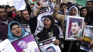 Manifestantes palestinos sujetan imágenes del prisionero  muerto por cáncer en un hospital israelí en Ramala,  Palestina.