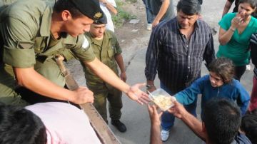Miembros del Ejército argentino entregan alimentos y colchones a filas de damnificados en La Plata (Argentina).