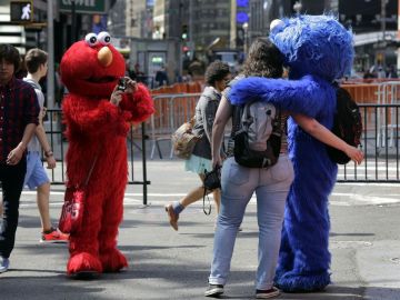 Un personaje de Elmo utiliza una cámara de una cliente para fotografiarla con un compañero que interpreta a “Cookie Monster” en la zona de Times Square.