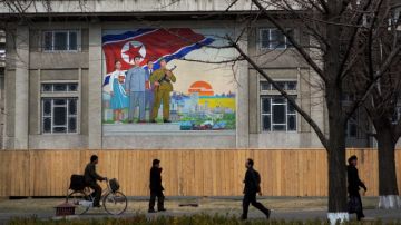 Ciudadanos norcoreanos pasan frente a un mural nacionalista en Pyongyang, Corea del Norte.
