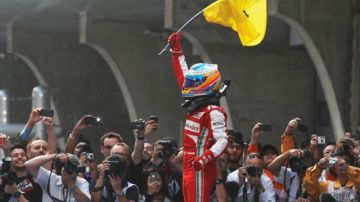 Fernando Alonso alza el banderín de su escudería desde el podio.