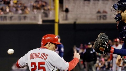 Peter Bourjos se barre en el home. El receptor de Mellizos,  Joe Mauer, espera la bola que va en camino.