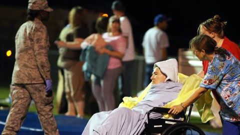 Varias personas asisten a anciana evacuada al campo deportivo de una escuela local en West, TExas, luego de la explosión e incendio en una fábrica de fertilizantes en Waco.