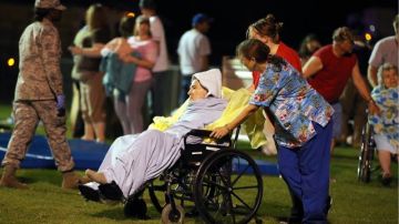 Varias personas asisten a anciana evacuada al campo deportivo de una escuela local en West, TExas, luego de la explosión e incendio en una fábrica de fertilizantes en Waco.
