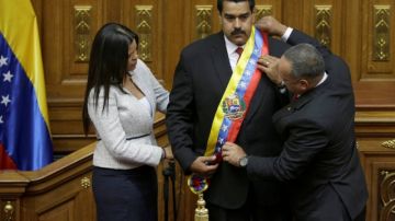 La hija del expresidente Chávez, Maria Gabriela, y el presidente de la Asamblea Nacional, Diosdado Cabello, colocan la banda presidencial a Nicolás Maduro.