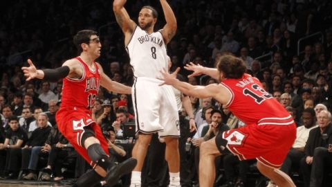 Deron Williams (centro), de Nets, salta para pasar el balón sobre la defensa de Toros en el tercer período.