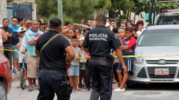 Policías aseguran el lugar donde encontraron los cadáveres de cinco hombres y dos mujeres en el interior de una casa en un barrio de bajos ingresos en la ciudad turística de Cancún, México, el domingo 14 de abril 2013.