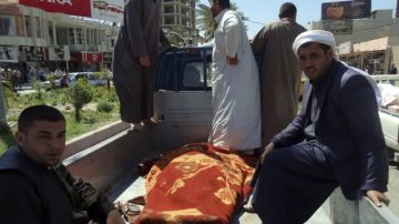 Un grupo de iraquíes transporta en camioneta el cuerpo de uno de los manifestantes caídos en enfrentamientos con el Ejército  en Kirkuk,  Irak, ayer.