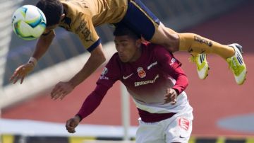 Luis Fuentes, de Pumas, 'vuela' por encima del ecuatoriano Joao Rojas (10) del Morelia en su enfrentamiento en la Liga Mexicana de Fútbol.