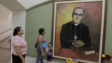 Salvadoreñas observan pintura del arzobispo asesinado de San Salvador Óscar Arnulfo Romero.