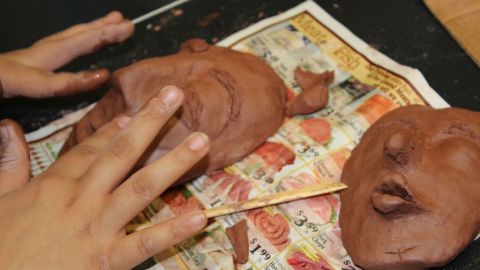 En el Centro Gads Hills, en Pilsen, Surizadny Hernández, estudiante de 15 años, usa sus dedos para crear una sonrisa en el rostro de una de las caras del fundador de la religión budista.