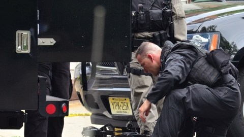 Un miembro del equipo Swat de la Policía estatal alista a un robot para entrar en una casa, donde un hombre tiene a varios menores como rehenes, en New Jersey, ayer.