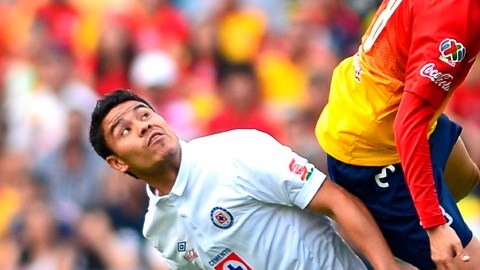 Pablo Barrera realiza una carga sobre Carlos Morales para evitar que gane el balón por alto.