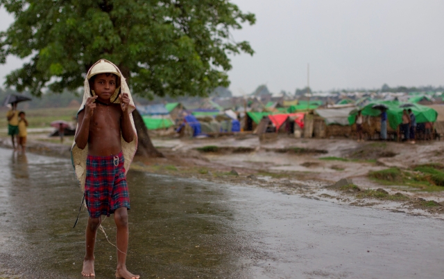 Un niño Rohingya usa una bolsa plástica para cubrirse de la lluvia generada por un ciclón que amenaza Myanmar.