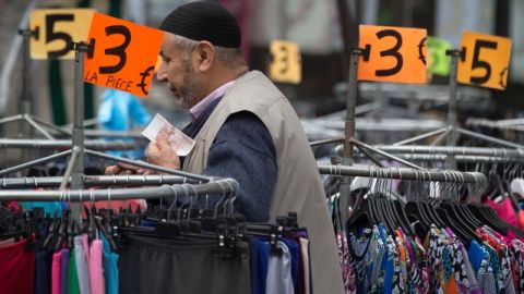Un hombre sostiene un billete de 10 euros para comprar en un mercado de París.
