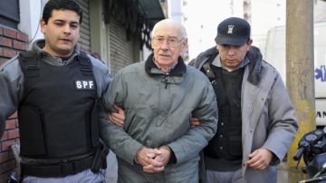 En una fotografía de archivo del  2012 se observa al ex dictador argentino Jorge Rafael Videla (c) escoltado por policías.