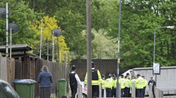 Varios agentes de la policía inspeccionan el escenario donde un soldado murió y otros dos resultaron heridos en un ataque con machete en Londres, Reino Unido.