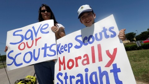 Terri Hall, izq, de San Antonio, Texas, junto a su hijo Nathaniel Hall, 8, sostienen carteles en contra de admitir exploradores gay, durante la reunión en Grapevine, Texas.
