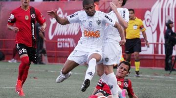 Juan Carlos Núñez, de Xolos, intenta frenar a Junior Machado, del  Mineiro, en duelo de ida de cuartos de final de la Copa Libertadores.