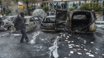 Un hombre examina un área donde varios carros fueron incendiados después de los disturbios