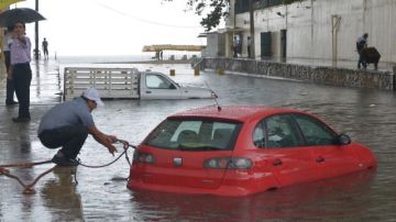 Una persona intenta rescatar su vehículo hoy en las inundaciones del puerto de Acapulco, estado mexicano de Guerrero, causadas por "Bárbara".