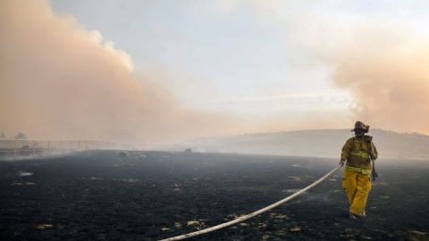 Un bombero trabaja en las labores de extinción de un incendio registrado a las afueras de Lancaster, California.