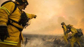 Varios bomberos trabajan en las labores de extinción de un incendio registrado a las afueras de Lancaster, California.