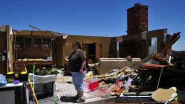 Tammy Wade looks over what is left of her home that was destroyed by the tornado's that ripped through El Reno Okla. Friday on Saturday June 1, 2013 in El Reno Okla. "We will rebuild because we love it out here" she said. (AP Photo/Nick Oxford)