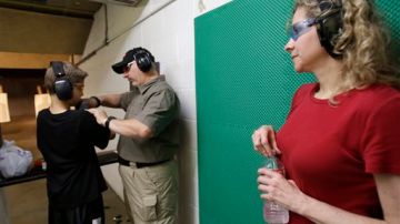 Cheryl Strain (d) observa como el  instructor Scott Stevens (c) muestra a su hijo Rory, cómo sostener una escopeta en un campo de tiro en Houston, Texas