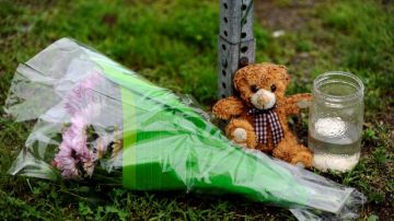 Un oso de peluche, una vela y unas flores adornan la entrada a la escuela Sandy Hook en recordación de las víctimas de la masacre.