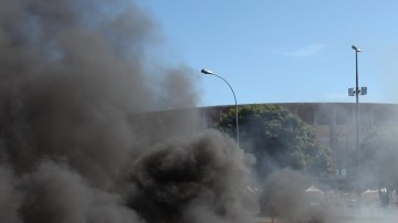 Una manifestante camina frente a una barricada de fuego durante una protesta frente al Estadio Nacional de Brasilia.