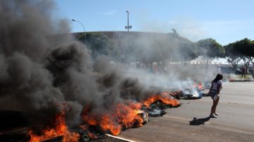 Una manifestante camina frente a una barricada de fuego durante una protesta frente al Estadio Nacional de Brasilia.