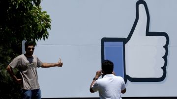 Un visitante se toma fotos frente al edificio en Menlo Park donde están las instalaciones de Facebook, con su característico símbolo.