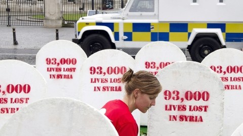 Una mujer  deja unas flores junto a unas lápidas de piedra que simbolizan los fallecidos en Siria, en Lough Erne, Irlanda del Norte, ayer.