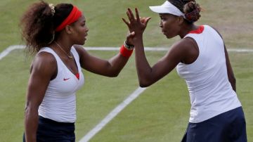 Serena Williams (izq.) y su hermana Venus se felicitan al derrotar a Sorana Cirstea y Simona Halep en los Olímpicos de 2012.