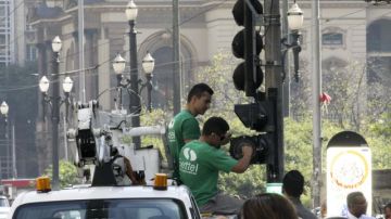 Empleados reparan un semáforo que fue vandalizado en Sao Paulo.