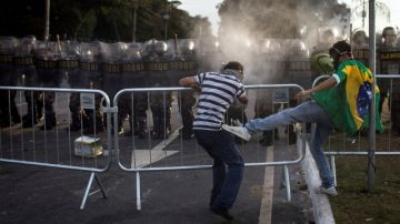 Un manifestante patea a otro para evitar que este rompa la barrera policial, durante las manifestaciones del sábado.