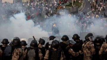 Centenares de personas corren por gases lacrimógenos de la policía, en el Estadio Minerao de Belo Horizonte.
