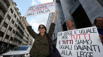 Dos mujeres reaccionan frente al tribunal después de un veredicto en contra de Silvio Berlusconi en Milán, Italia. Hubo protestas a favor y en contra de Berlusconi.