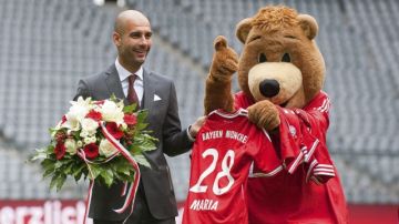 El nuevo entrenador del Bayern Múnich, el español Pep Guardiola, posa junto a la mascota del equipo durante su presentación ante la prensa.