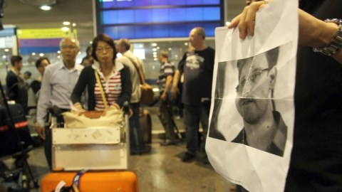Periodistas en un aeropuerto moscovita muestran la foto de Snowden a los viajeros de Hong Kong.
