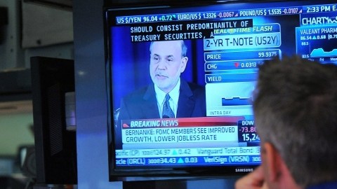 Un comerciante escucha al presidente de la Fed, Ben Bernanke, en la sede de la Bolsa de Valores.