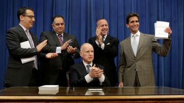 El gobernador de California Jerry Brown ha firmado en el Capitolio, en Sacramento. el nuevo presupuesto que restaura millones de dólares para programas de servicios sociales cortados durante la recesión. El senador Mark Leno (d) muestra una copia del mismo.