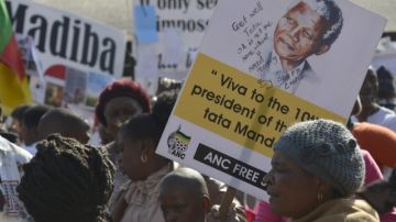 Carteles con mensajes para Nelson Mandela, canciones y oraciones, flores y velas  son llevados  por la gente que se reúne fuera del hospital donde está ingresado  Madiba.