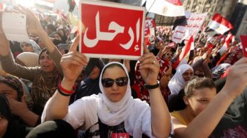 Egipcios, detractores del presidente Mursi, muestran pequeñas pancartas con la palabra 'Vete' en árabe, durante una protesta en la plaza Tahrir, en El Cairo.