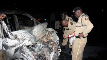 Policía de Uganda inspecciona el auto destrozado que al chocar con un camión de gasolina la explosión mató a 29 personas.