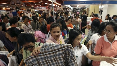 Varios consumidores compran ropa en una feria comercial. La economía de China está retrocediendo y la participación de inversionistas en el mercado ya muestra evidencia de retirada.