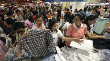 Varios consumidores compran ropa en una feria comercial. La economía de China está retrocediendo y la participación de inversionistas en el mercado ya muestra evidencia de retirada.
